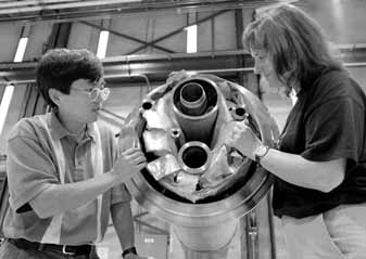 Yuenian Huan and Marsha Schmidt inspect a superconducting quadrapole magnet for the LHC