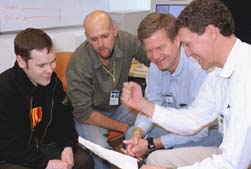 Co-spokesperson Bill Louis (right) gets a charge from examining the beam report with (from left) Gordon McGregor, Richard Van de Water and Geoff Mills of Los Alamos